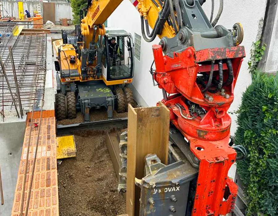 Bagger mit Movax-Rammgerät in enger Baustellensituation